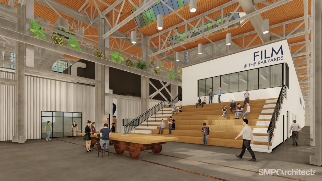 Digital rendering of a converted rail yard with bleacher seating and people socializing.
